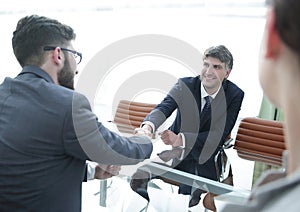 Handshake across the table of financial partners