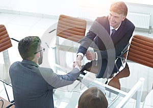 Handshake across the table of financial partners