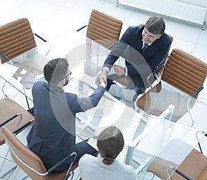 Handshake across the table of financial partners