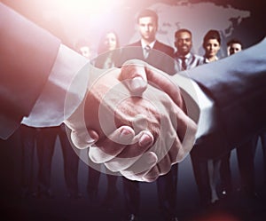 Handshake on the background group of business people in dark colors