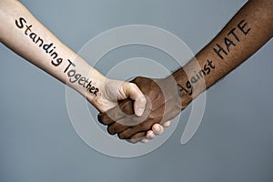 Handshake between black and white human woman and male hands with the message text Standing Together against HATE