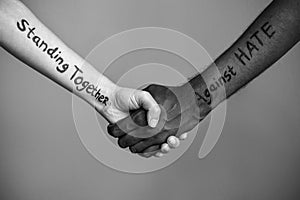 Handshake between black and white human woman and male hands with the message text Standing Together against HATE. Black and white