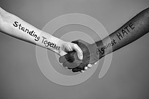 Handshake between black and white human woman and male hands with the message text Standing Together against HATE. Black and white