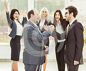 Handshake of business partners on background of cheering business team