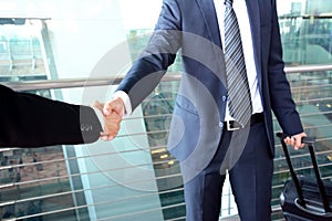 Handshake of businessmen at the airport - business travel concept