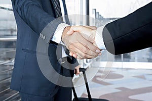 Handshake of businessmen at the airport - business travel concept