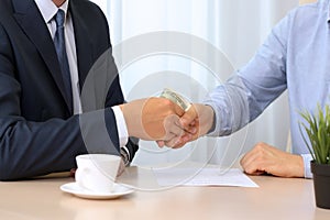 Handshake of businessmen with money. Blue background behind
