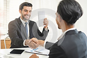 Handshake, caucasian male giving financial reward in an envelope, business letter extra salary to company employee, asian manager