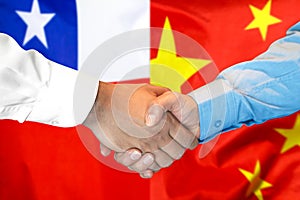 Handshake on Chile and China flag background