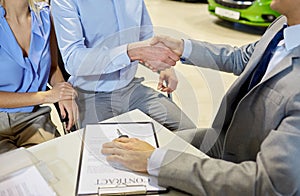 Handshake of customer and car dealer in auto salon