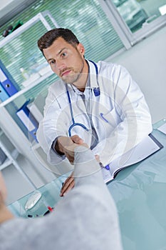 Handshake doctor and patient sitting at table