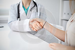 Handshake doctor and patient sitting at the table, closeup