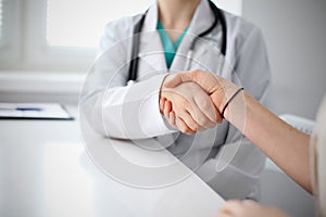 Handshake doctor and patient sitting at the table, closeup