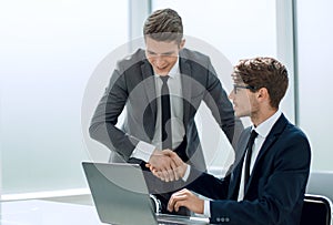 Handshake of the employees near the desktop