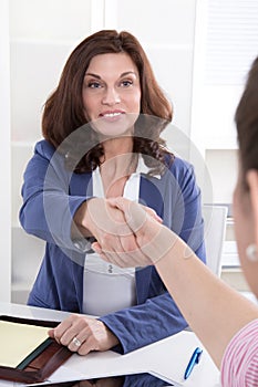 Handshake: Female financial adviser with customer.