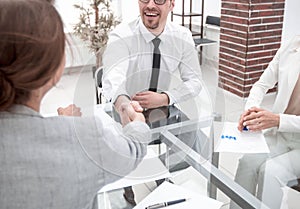 Handshake financial partners sitting at the office Desk