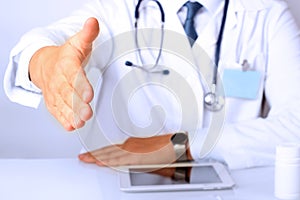 Handshake Gesture from Doctor in a white labcoat and stethoscope on his sholder photo