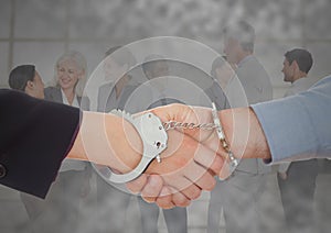 Handshake with handcuffs in front of business people with grunge overlay