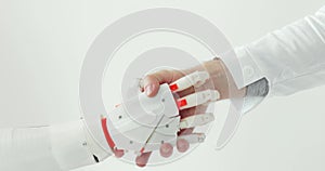 Handshake of human hand in white coat and robotic prosthesis hand on white background.