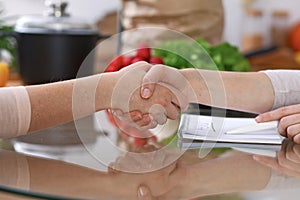 Handshake in the kitchen, closeup. Two women agreed about menu. Cooking and friendship concept.