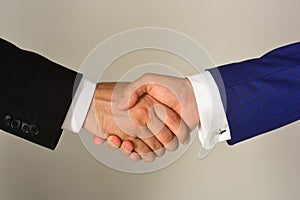 Handshake on light grey background. Businessmen wear smart suits