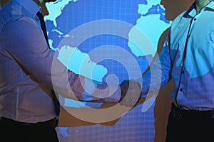 Handshake with map of the world in background. two businessmen on the background of the world map shake hands, the