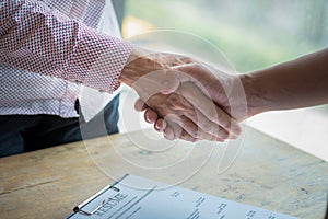 Handshake success job interviewing. Job applicant having interview. Shaking Hand With Resume On Desk. Employer giving an handshake