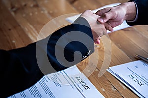 Handshake success job interviewing. Job applicant having interview. Shaking Hand With Resume On Desk. Employer giving an handshake