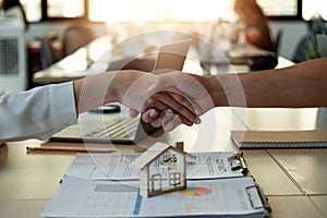 Handshake a successful real estate transaction in an office. Business people shake hands after signing a house purchase