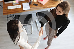 Handshake of two business women in office top view