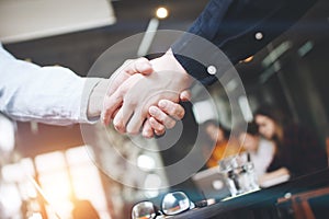 Handshake of two businessmen close-up, on a background of modern loft office