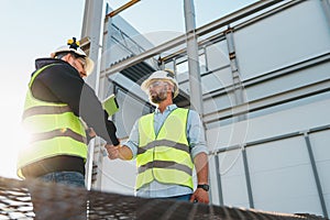 Handshake of two engineers wearing safety helmet and protect sunglasses on outdoors construction site. Meeting and hand shake of