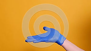 Handshake of two people in blue medical gloves on a yellow background