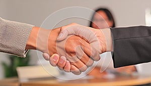 A handshake between two people on a blurred background of a meeting room