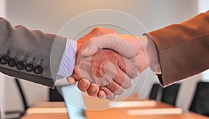 A handshake between two people on a blurred background of a meeting room