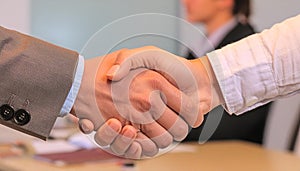 A handshake between two people on a blurred background of a meeting room