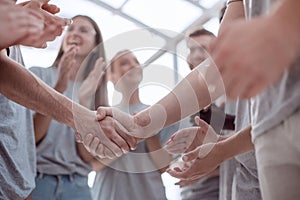 Handshake of young people on the background of the applauding team