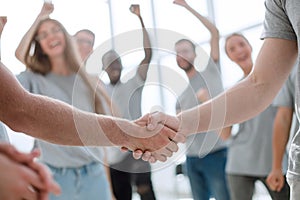 Handshake of young people on the background of the jubilant team