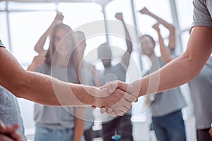 Handshake of young people on the background of the jubilant team