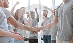 Handshake of young people on the background of the jubilant team