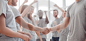 Handshake of young people on the background of the jubilant team