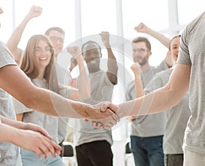 Handshake of young people on the background of the jubilant team