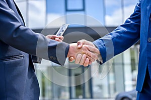 Handshakes against new business center close up