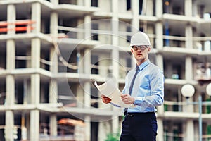 Handsom construction engineer at the construction site looking at the camera