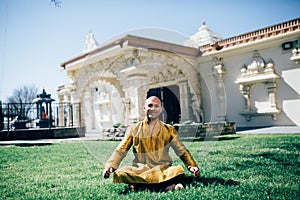 Handsom Indian Man Sitting and Smile in a Gold Kurta at the Temple