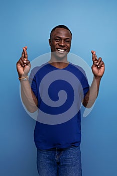 handsome 25s african guy in casual blue t-shirt crossed his fingers