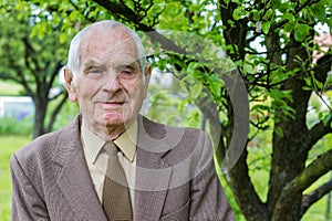 Handsome 80 plus year old senior man posing for a portrait in his garden