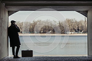 handsome adult man with suitcase smoking in tunnel in front of