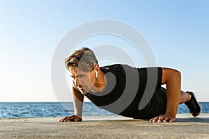 handsome adult sportsman with wireless earphones doing push ups