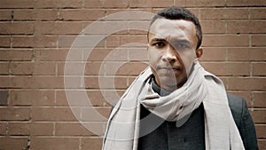 Handsome African American adult man says no shaking his head. Brick wall on background. Slow motion portrait shot.